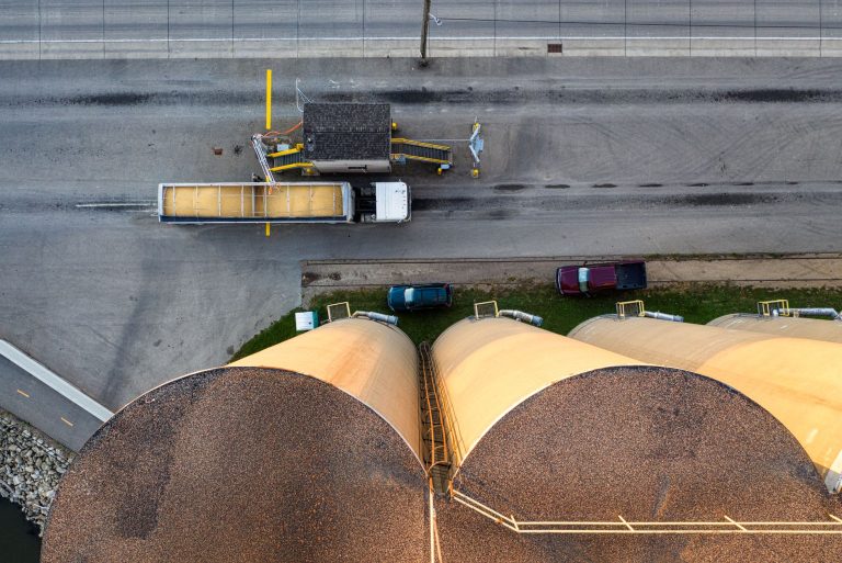 Vista aérea de silos industriais ao lado de um caminhão em uma unidade de armazenamento de grãos.